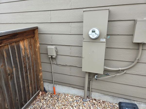 Electric meter and utility boxes on a house exterior.