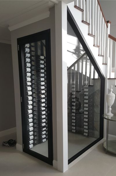 specialized custom made glass, refrigerated climate controlled wine cellar under a staircase