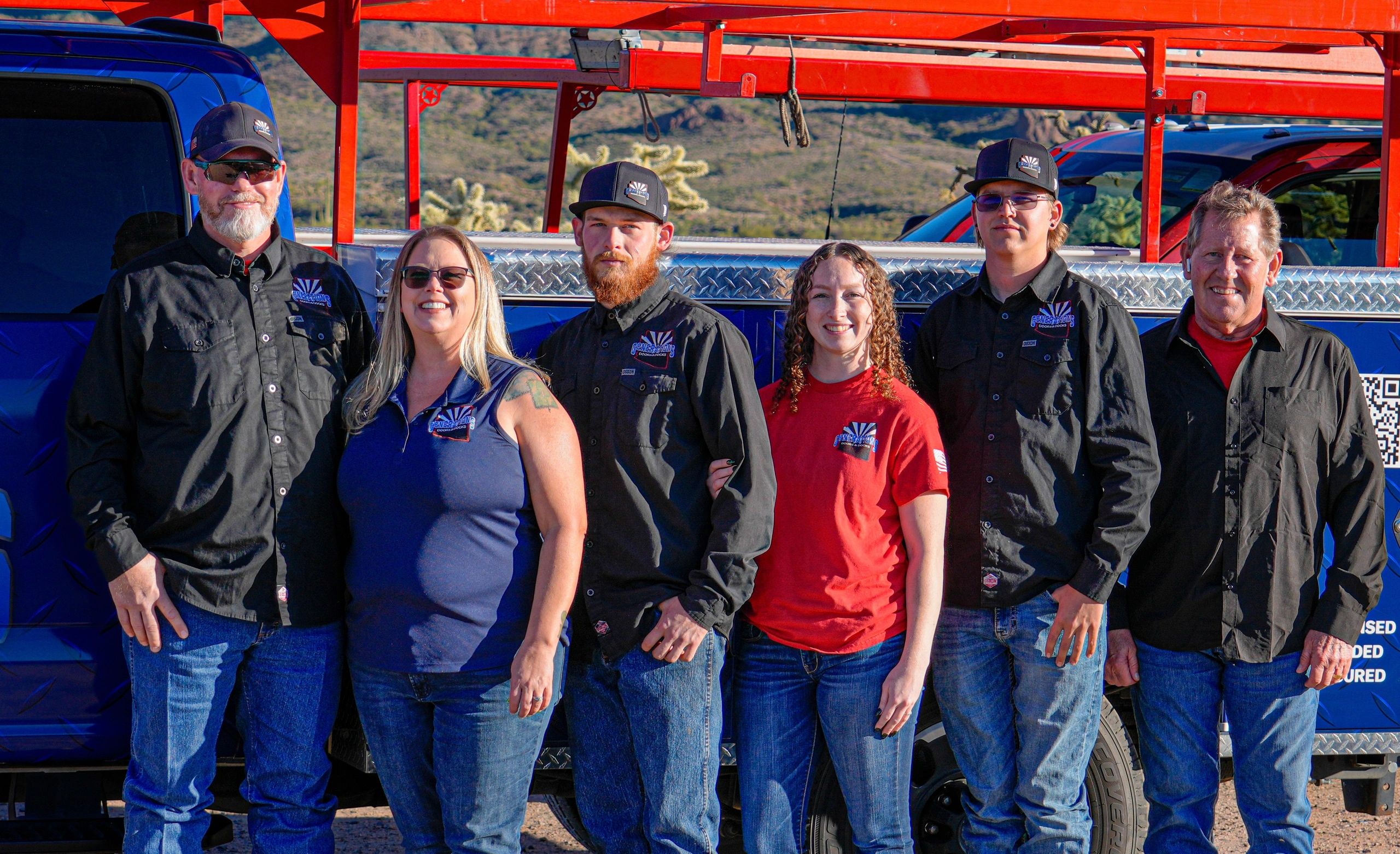 Group of six people standing in front of trucks outdoors.