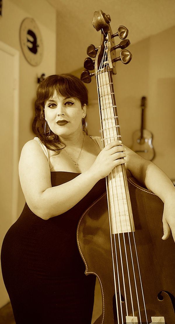 Woman posing with a double bass in sepia tone.