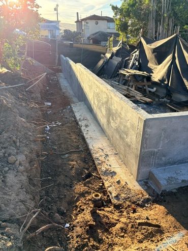 Poured-in-place concrete wall along a residential property during construction.