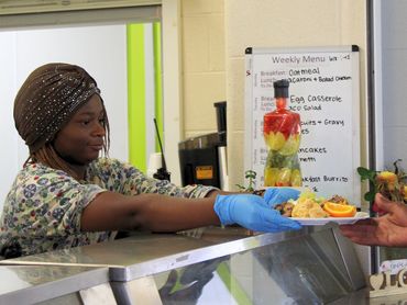 teen handing lunch to a client at Crosslines Community Outreach for a Community Ambassador Project