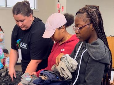 Teens folding clothes for a Community Ambassador Project