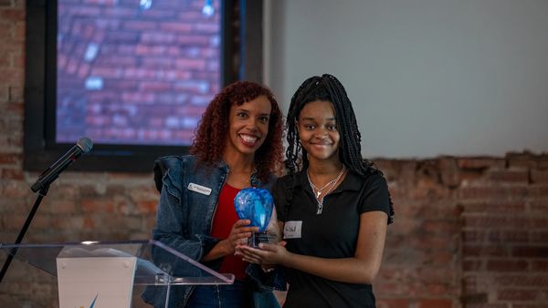 Dr. Johnston smiling with Ambassador, TraShell as she receives her award