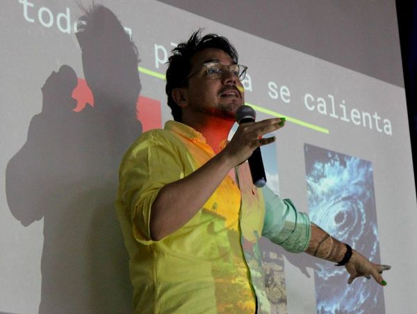 Man in yellow shirt giving a presentation with a microphone and pointing at a projection.