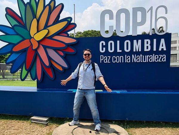 Man posing in front of COP16 Colombia environmental conference sign.