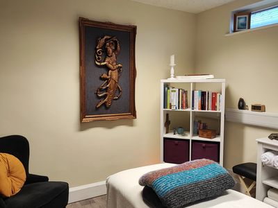 A therapy room with an ornate wooden carving of the goddess Juitan on the wall.