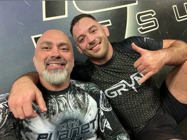 Two smiling men in athletic gear posing for a selfie after training.