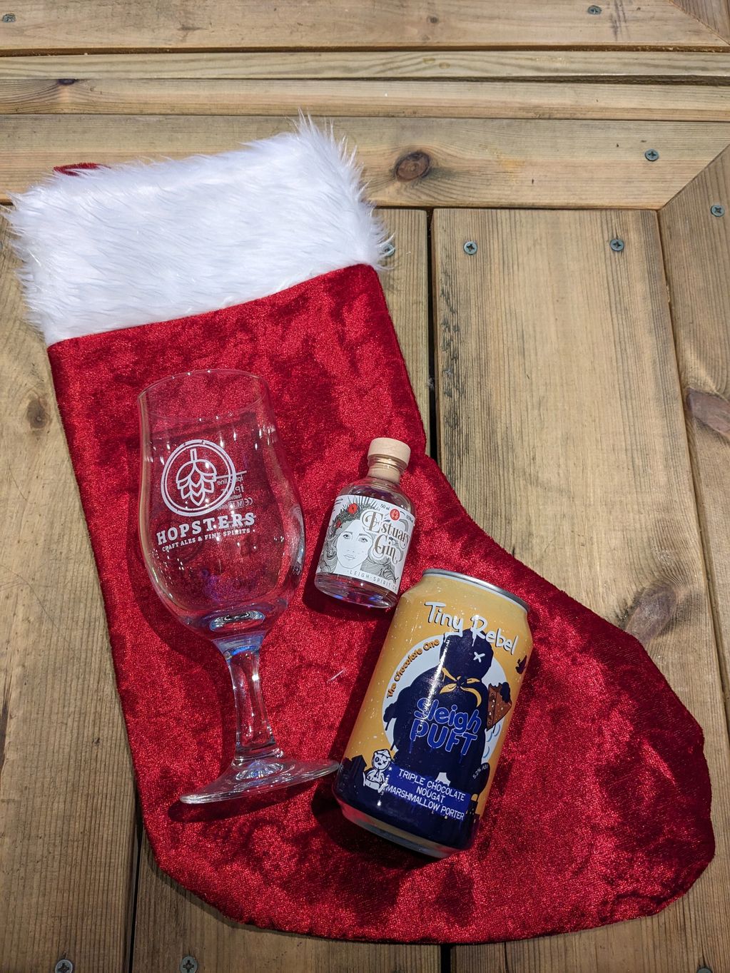 Christmas stocking with a glass, mini gin bottle, and a craft beer can.