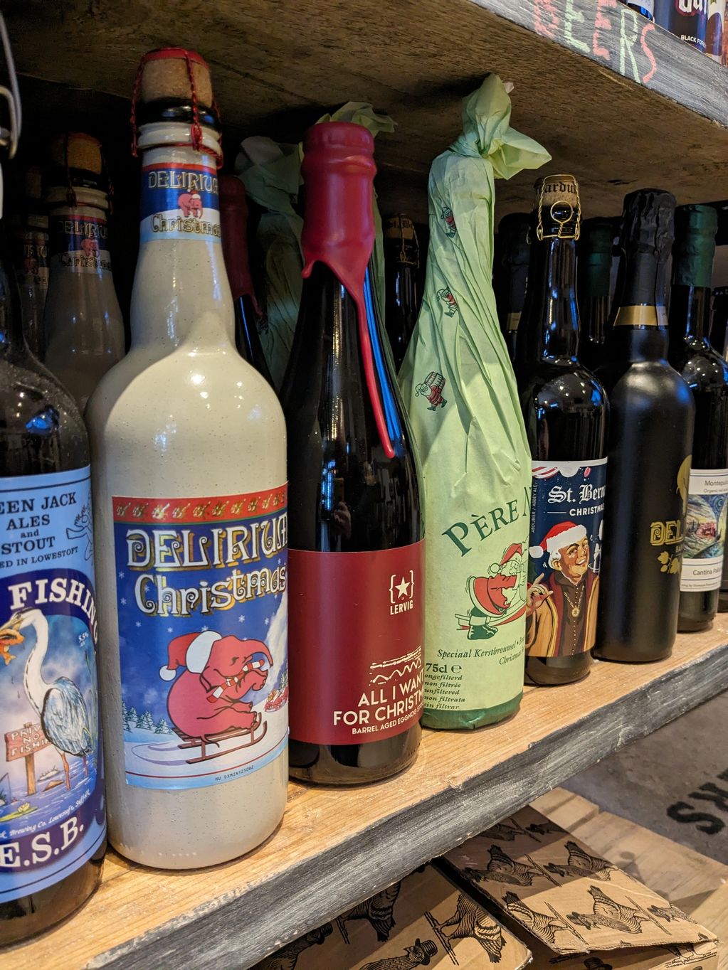 A shelf of assorted craft beers with festive holiday labels and unique packaging.