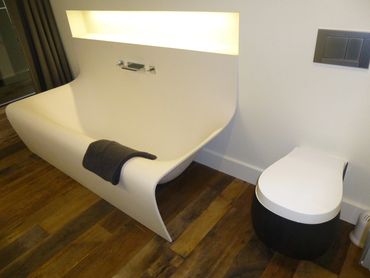 Modern bathroom with unique curved bathtub and toilet.