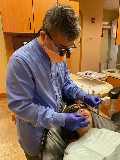 Dentist examining a patient's teeth with dental tools in a clinic.