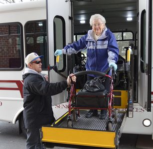 A passenger is assisted off of a township bus.