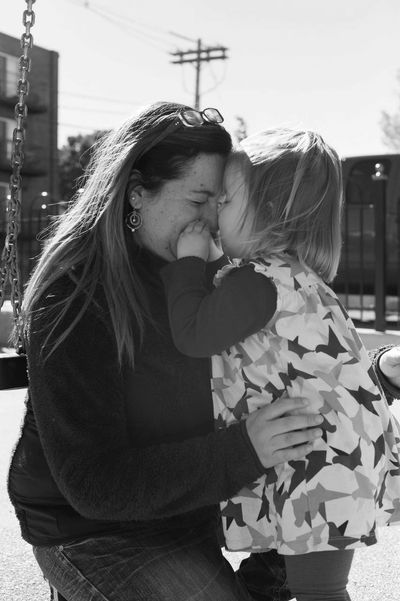 A woman and child share a tender moment on a swing set.