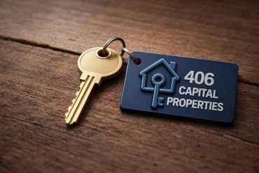 Golden key with a blue keychain labeled '406 Capital Properties' on a wooden surface.