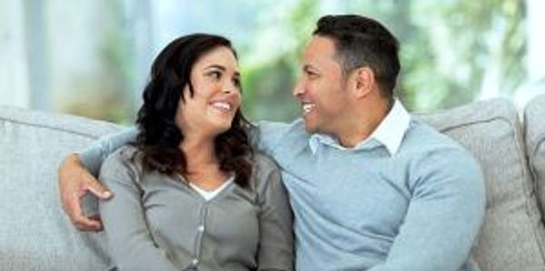 Couple smiling and talking on a couch.