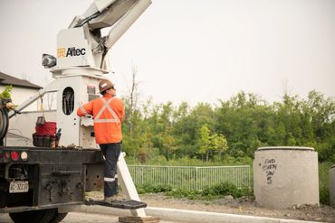 Worker in orange safety gear standing on a utility truck platform.