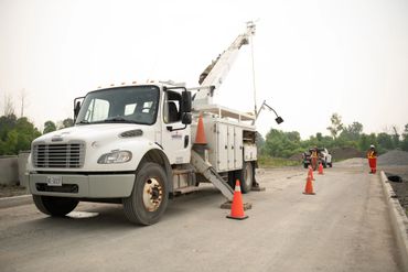 Utility truck with workers and safety cones on a construction site.
