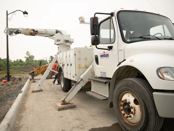 A utility truck with stabilizers deployed at a construction site.