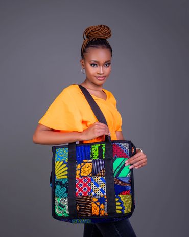 A woman in an orange top holding a colorful patchwork bag.