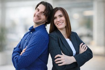 professional duo in a business setting, smiling, in business attire against a light background