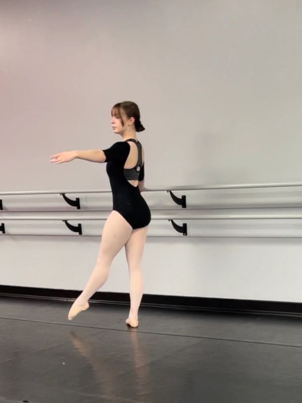 Ballet dancer practicing in a studio with barre and mirror.