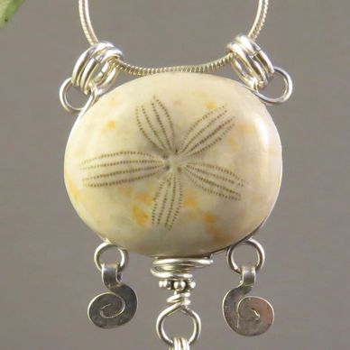 Unique pendant necklace made with a fossilized sand dollar, pearls, and a carved jade leaf. AlmaMia