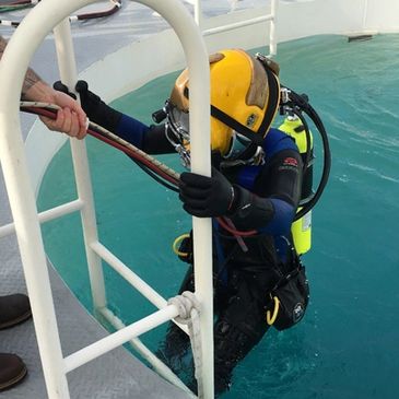 scuba diver in a yellow helmet emerging from a dive tank