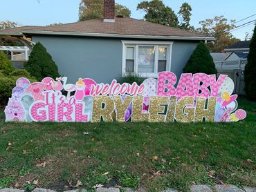 Welcome baby girl yard sign outside a house.