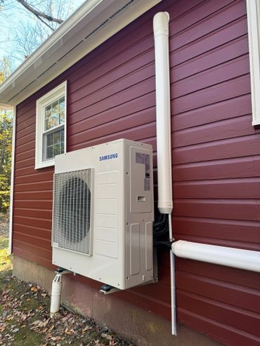 Samsung air conditioning unit installed on red wooden house exterior.
