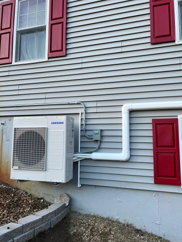 Samsung air conditioning unit mounted on a house with red shutters.