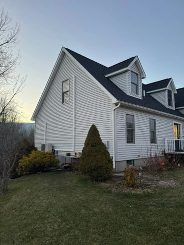A white house with dark roof shingles during dusk on a clear day.