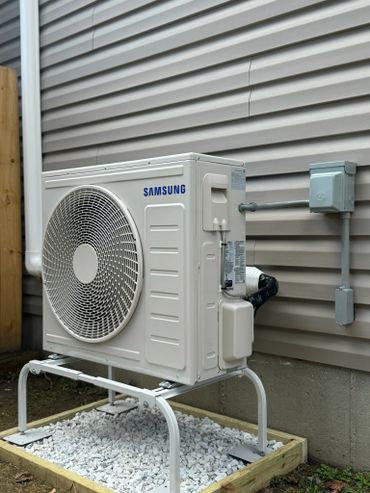 Samsung outdoor air conditioning unit installed on a gravel bed.