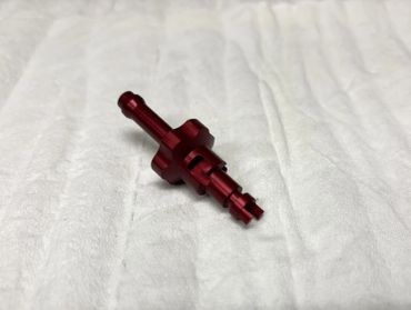 Small red metal part on a white surface.