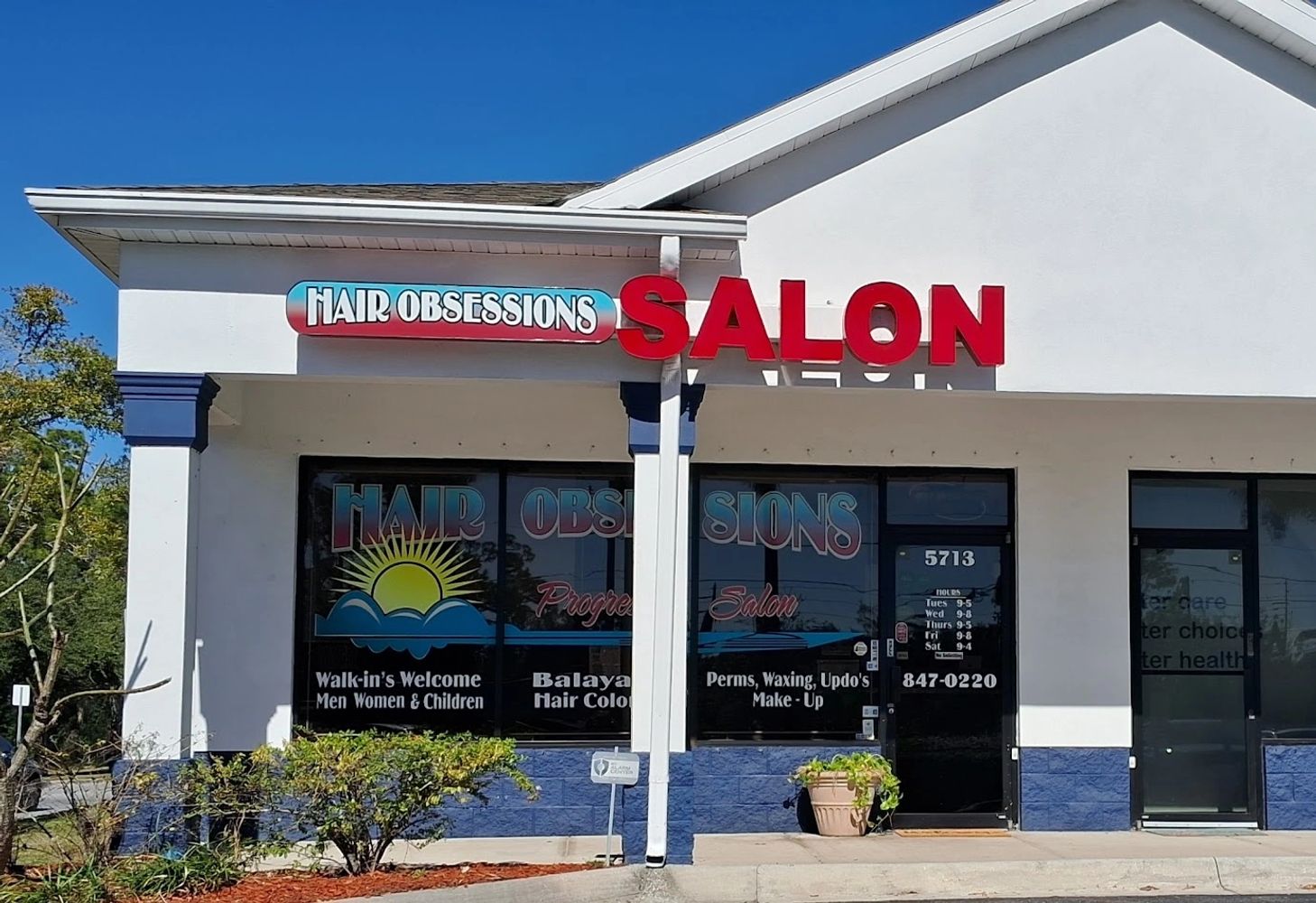 Exterior view of Hair Obsessions Salon with colorful signage on a sunny day.