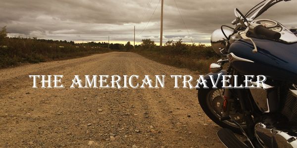 Motorcycle on a gravel road with text 'The American Traveler'.