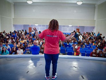 Speaker addressing a large audience in an auditorium.