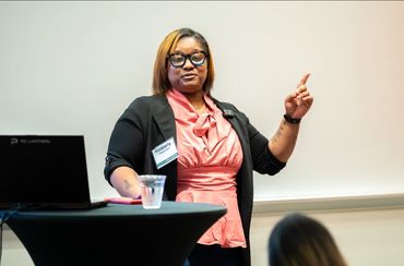 Woman named Kimberly giving a presentation with a laptop and water glass nearby.