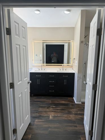 Modern bathroom with double sinks and illuminated mirror.