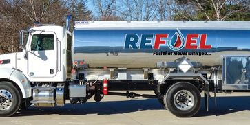 A white fuel tanker truck with 'REFUEL' branding parked outdoors.