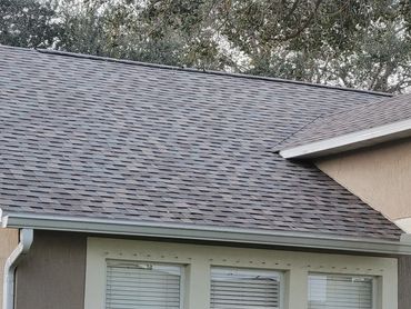 Close-up of a house roof with gray shingles and white gutters.