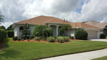 Single-story house with a well-maintained garden and manicured lawn under a cloudy sky.