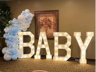Illuminated letters spelling BABY with blue and white balloon decorations.