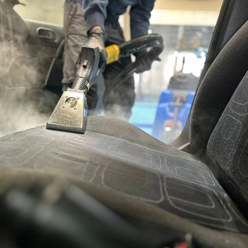 Cleaning a car seat with a steam cleaner.
