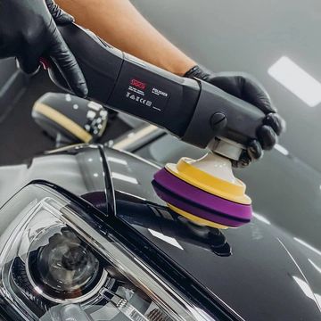 Polishing a car's black surface with a buffer.