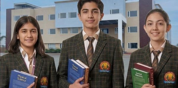 Three students in school uniforms holding textbooks, standing in front of a building.