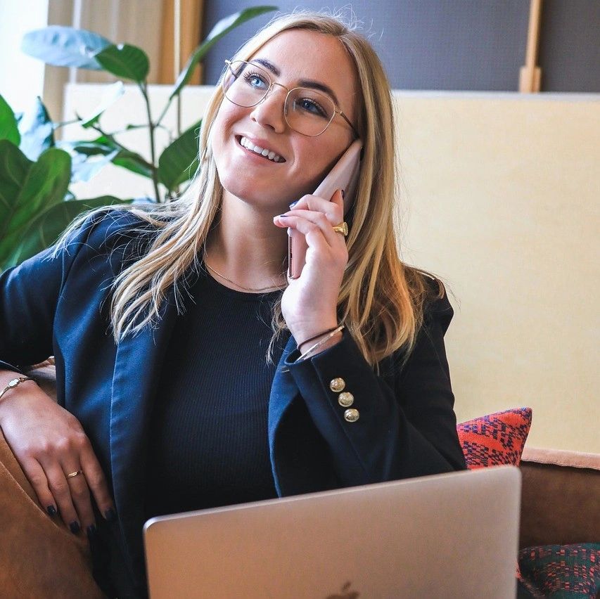 a young woman on the phone in front of her laptop