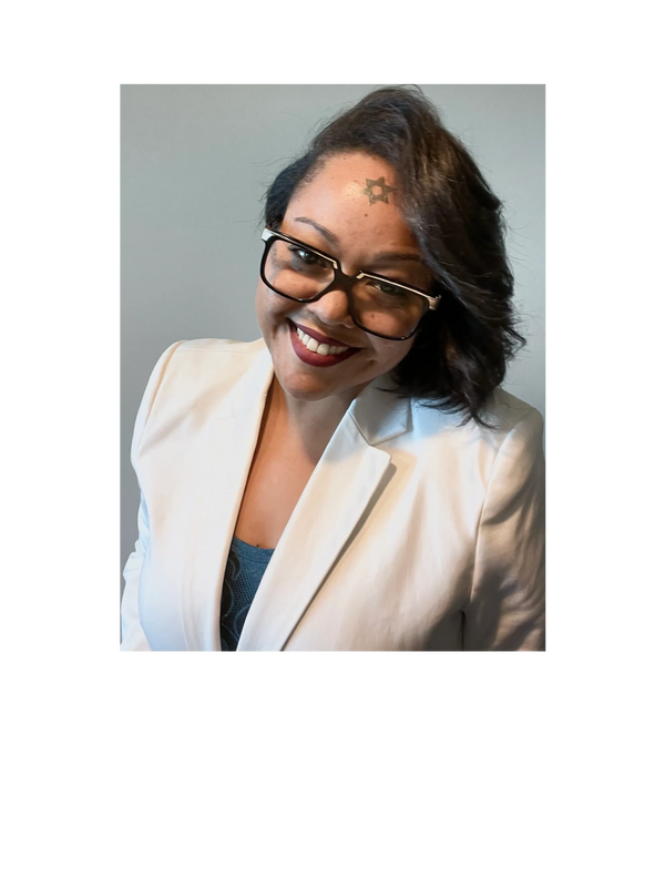 Smiling woman with glasses wearing a white blazer.