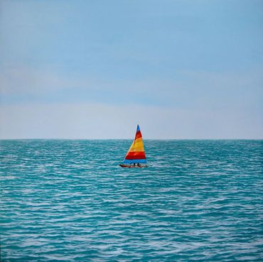 Sailboat with colorfully striped sails on a clear day with a light breeze and blue sky