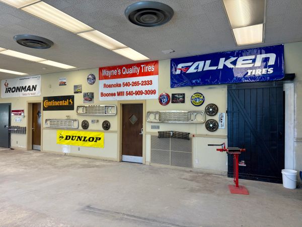 Interior wall of a tire shop with various tire brand signs and car parts.